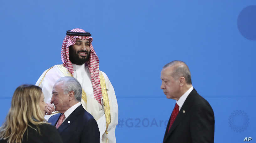 Saudi Arabia's Crown Prince Mohammed bin Salman smiles as Turkey's President Recep Tayyip Erdogan, right, passes by during the family photo of the G20 Leader's Summit at the Costa Salguero Center in Buenos Aires, Argentina, Friday, Nov. 30, 2018. (AP Photo/Ricardo Mazalan)